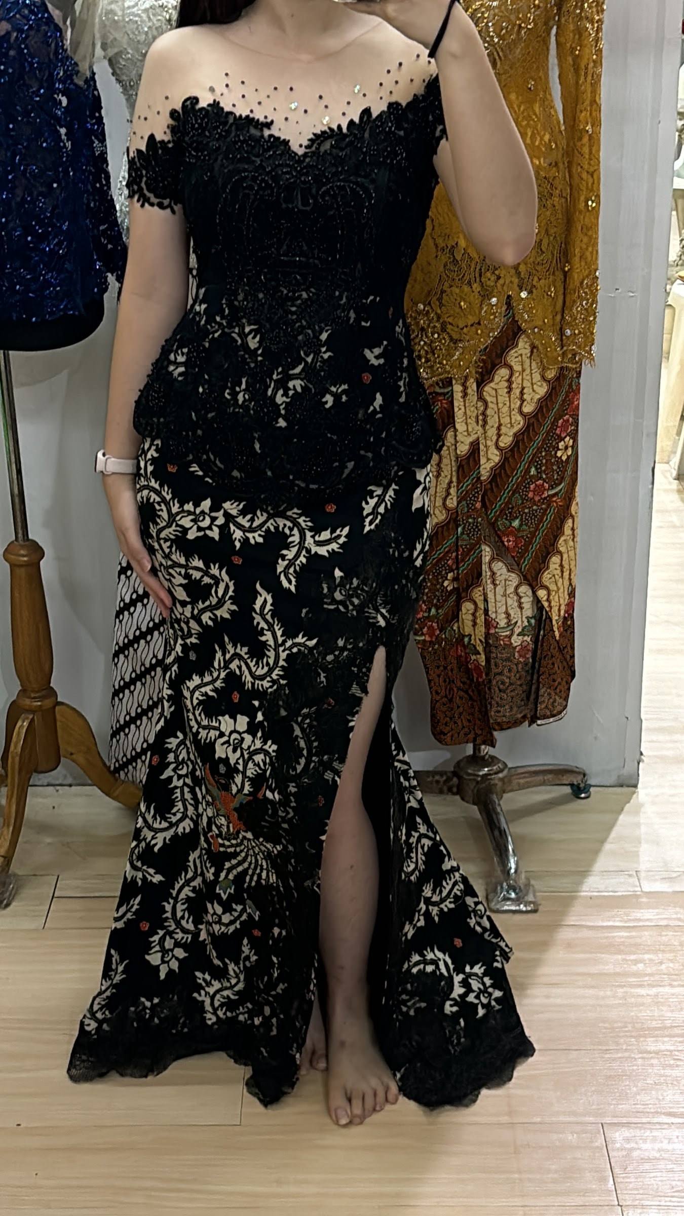 Kebaya renda hitam dengan rok batik berbelahan di manekin