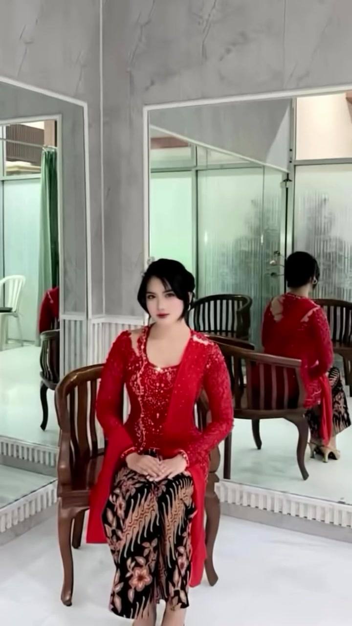 Kebaya merah lengan panjang dengan kain batik, difoto di ruang pas butik
