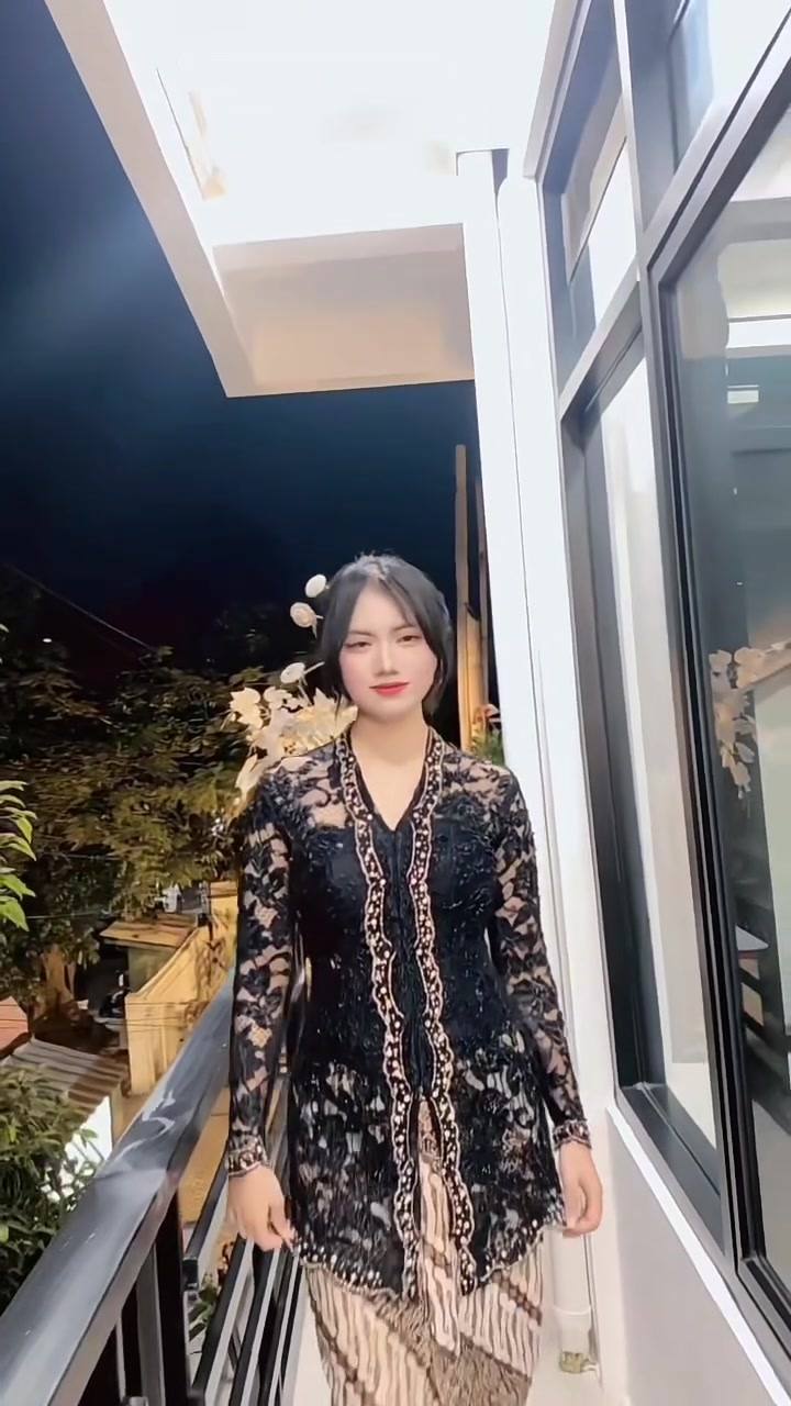Kebaya biru tua berpayet dengan kain batik, difoto di teras pada malam hari